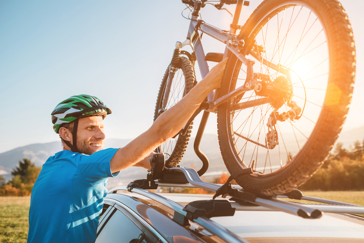 personne qui charge un vélo sur le toit de sa voiture